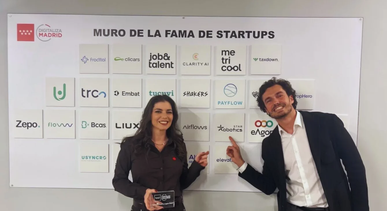 Representante de Star Robotics señalanel logo de la empresa en el Muro de la Fama de Startups de Madrid