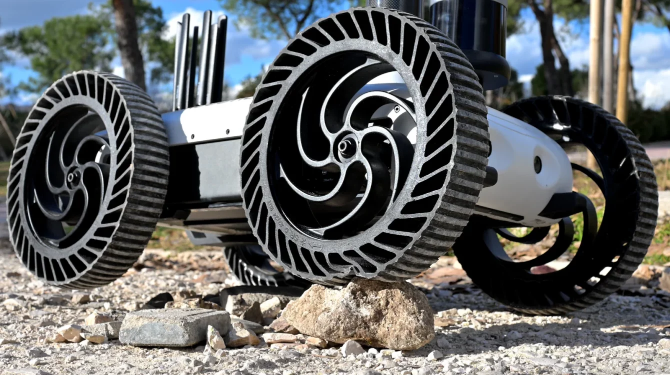 Close-up of the Watchbot robot's airless wheels crossing rocky, gravelly ground